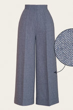 Load image into Gallery viewer, A pair of high-waisted, wide-leg trousers in a textured slate blue-gray fabric, shown on a light beige background with a circular zoom-in detail of the herringbone weave on the right.