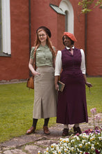 Load image into Gallery viewer, Two women in vintage clothing standing outdoors with a red building in the background.