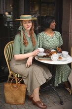 Load image into Gallery viewer, Two women in vintage attire sitting at a table with food and drinks in an outdoor setting.