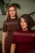 Load image into Gallery viewer, Two women wearing vintage-style knit dresses with diamond-patterned yoke details, posed indoors against a softly lit background with plants and a staircase visible.