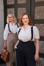 Load image into Gallery viewer, Two women in vintage attire standing in front of a textured wall.