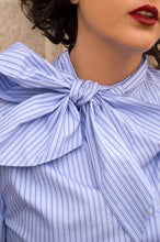 Load image into Gallery viewer, Close-up of a person wearing a blue and white striped shirt with a large bow detail.