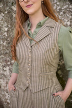 Load image into Gallery viewer, Woman wearing a striped vest over a green shirt against a stone wall background
