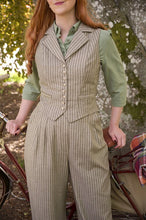 Load image into Gallery viewer, Woman in a vintage-style outfit with a striped suit and green shirt, standing next to a bicycle.
