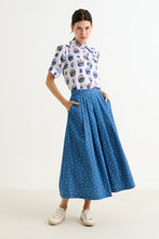Load image into Gallery viewer, Woman wearing a patterned shirt and blue skirt on a white background