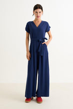 Load image into Gallery viewer, Woman wearing a blue jumpsuit on a white background