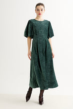 Load image into Gallery viewer, A woman modeling a dark green velvet midi dress with short puff sleeves, a round neckline, and a gathered waist, paired with dark pointed-toe heels against a plain white studio background.