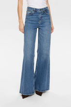 Load image into Gallery viewer, Blue flared jeans worn by a person on a white background