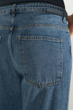 Load image into Gallery viewer, Close-up of the back waistband and pocket area of blue denim jeans, showing a dark belt and the back pocket stitching.