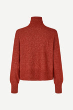 Load image into Gallery viewer, A rust-red knit turtleneck sweater shown from the back, featuring long sleeves and a ribbed hem, displayed on a clean off-white background.