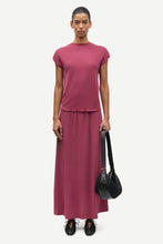 Load image into Gallery viewer, Woman in a pink top and skirt holding a black handbag on a white background