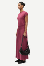 Load image into Gallery viewer, Woman in a pink top and skirt holding a black handbag on a white background