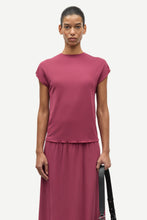 Load image into Gallery viewer, Woman in a pink top and skirt holding a black handbag on a white background