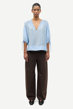 Load image into Gallery viewer, Person wearing a light blue top and brown pants on a white background