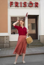 Load image into Gallery viewer, Woman in a red dress standing in front of a building with a neon sign reading 'Frisor'.