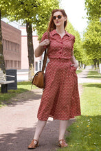 Load image into Gallery viewer, Woman in a red patterned outfit walking outdoors on a sunny day.